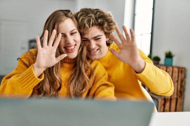 Beyaz bir çift gülümsüyor. Evde video görüşmesi yapıyorlar.