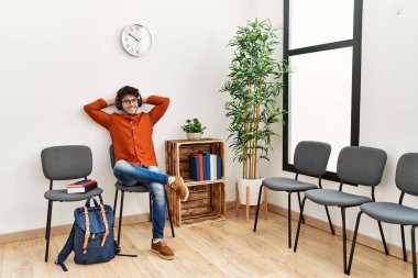 Genç İspanyol adam, bekleme odasında müzik dinlerken kendinden emin bir şekilde gülümsüyor.