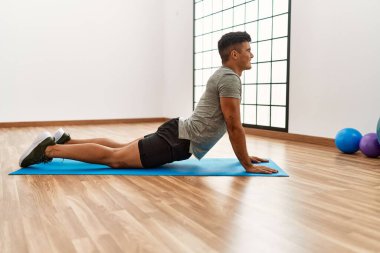 Genç İspanyol adam gülümsüyor spor merkezinde esniyor.