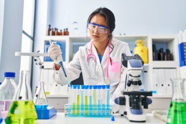 Young chinese woman wearing scientist uniform working at laboratory