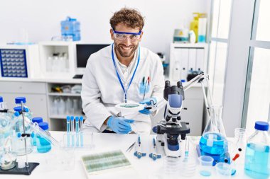 Laboratuvarda Loupe 'u kullanan İspanyol bir bilim adamı üniforması giyiyor.