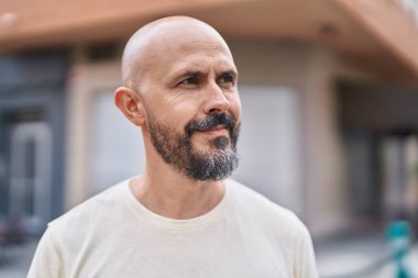 Genç kel adam ciddi bir ifadeyle caddeye bakıyor.