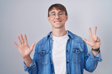 Caucasian blond man standing wearing glasses showing and pointing up with fingers number eight while smiling confident and happy. 