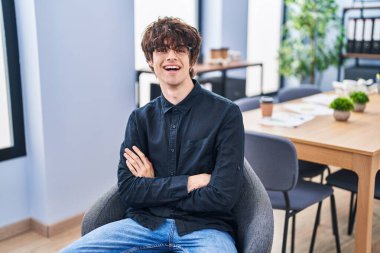 Genç İspanyol iş adamı kollarını kavuşturup ofiste oturuyor.