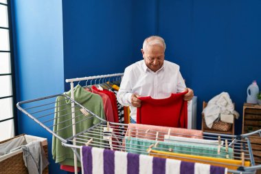 Son sınıf öğrencisi gülümsüyor çamaşırhanede çamaşır ipine kendinden emin bir şekilde asılıyor.