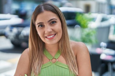 Young beautiful hispanic woman smiling confident standing at coffee shop terrace clipart