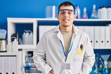 Young man scientist smiling confident at laboratory