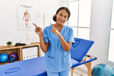 Güzel İspanyol fizyoterapist kadın ağrı kesici kliniğinde gülümsüyor ve kameraya bakıyor.. 