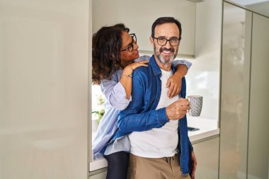 Orta yaşlı İspanyol çift mutfakta kahve içerek birbirlerine sarılıyorlar.