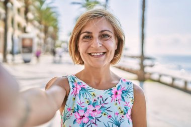 Orta yaşlı, güzel bir kadın. Deniz kenarında kendine güvenen.