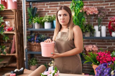 Çiçekçi dükkanında çalışan genç sarışın kadın şüpheci ve gergin, sorun yüzünden surat asıyor. negatif kişi. 