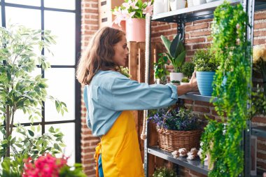 Çiçekçide raf düzenleyen güzel İspanyol kadın.