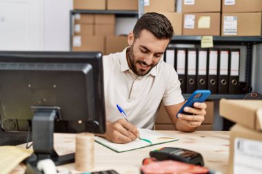 Depoda akıllı telefon kullanarak gülümseyen İspanyol genç adam.