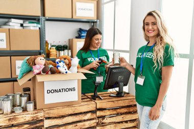 İki gönüllü kadın, hayır kurumunda çalışmaktan mutlu gülümsüyor..