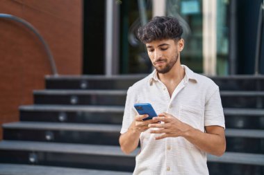 Sokakta akıllı telefon kullanan genç bir Arap.
