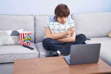 Laptopta korku filmi izleyen İspanyol genç adam komik suratıyla yanaklarını şişiriyor. Ağzı havayla şişer, havayı yakalar.. 