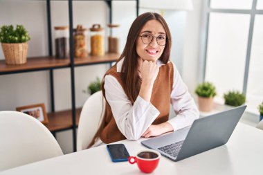 Evdeki masada dizüstü bilgisayar kullanan güzel bir İspanyol kadın.
