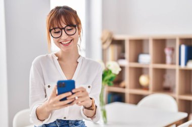 Evde akıllı telefon kullanan kendine güvenen genç bir kadın.