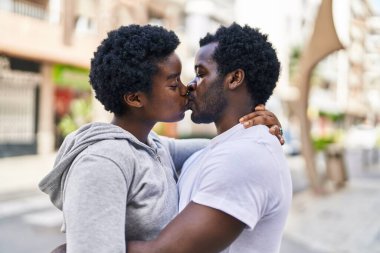 African american man and woman couple hugging each other and kissing at street