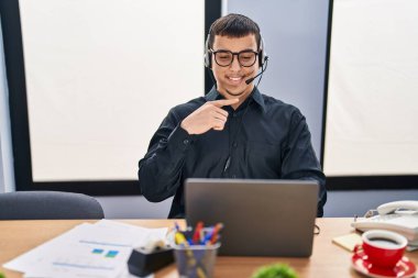 Young arab man wearing call center agent headset smiling happy pointing with hand and finger 
