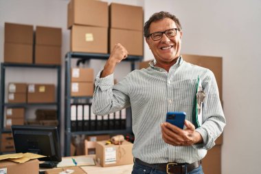 Ofiste akıllı telefon kullanan orta yaşlı bir iş adamı.