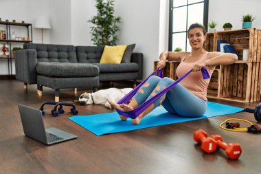 Evde elastik bant kullanan ve kendine güvenen genç bir kadın.