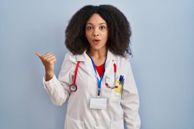 Doktor üniforması ve steteskop giyen genç Afro-Amerikan kadın elini kaldırdığında şaşırdı ve ağzı açık kaldı.. 