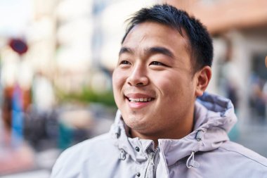Young chinese man smiling confident standing at street