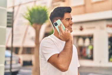 Genç İspanyol adam gülümsüyor. Kendine güveniyor. Sokakta akıllı telefondan konuşuyor.