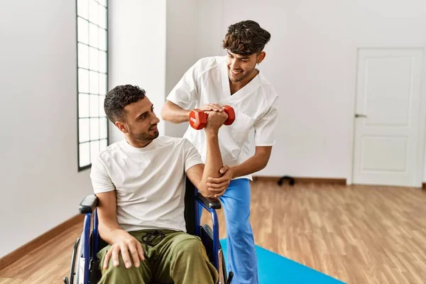 Spanyol Erkek Fizyoterapist Hasta Tekerlekli Sandalyede Oturmuş Klinikteki Halterleri Kullanarak — Stok fotoğraf
