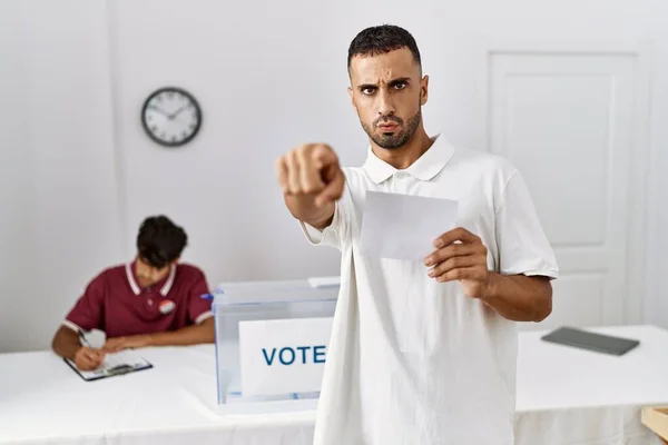 Young Hispanic Man Voting Putting Envelop Ballot Box Pointing Finger — Fotografia de Stock