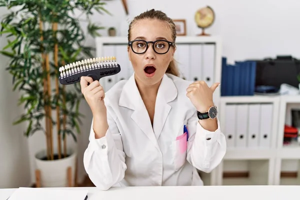 Young Caucasian Woman Holding Teeth Whitening Palette Surprised Pointing Hand — Stock Photo, Image