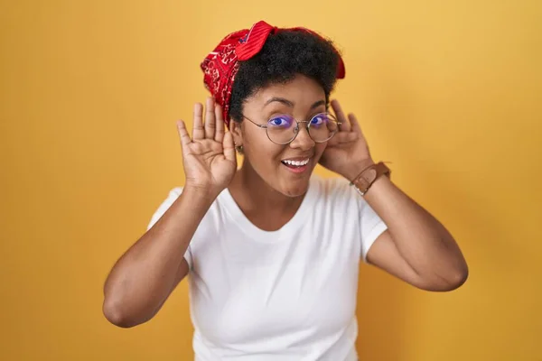 Joven Mujer Afroamericana Pie Sobre Fondo Amarillo Tratando Escuchar Ambas —  Fotos de Stock