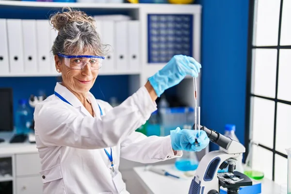 中年妇女科学家在实验室测量液体 — 图库照片