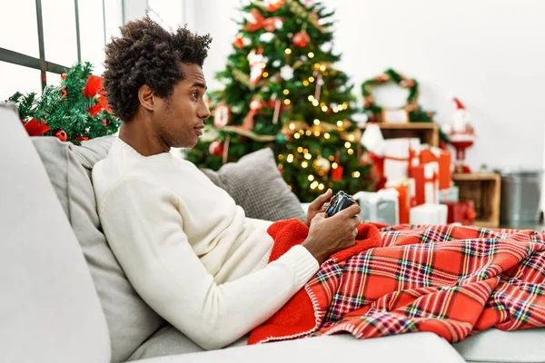 Joven Hombre Afroamericano Jugando Videojuego Sentado Sofá Por Árbol Navidad — Foto de Stock