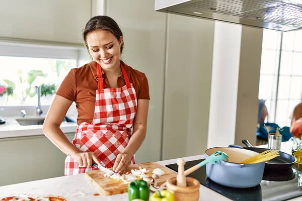 Νεαρή Όμορφη Ισπανίδα Γυναίκα Μαγειρεύει Σπαγγέτι Κόβοντας Κρεμμύδι Στην Κουζίνα — Φωτογραφία Αρχείου