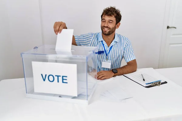 若いヒスパニック系政党の労働者は 選挙の大学で投票箱に投票を入れて幸せ笑顔 — ストック写真