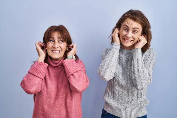 Mother Daughter Standing Blue Background Covering Ears Fingers Annoyed Expression — Stockfoto