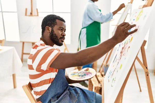 アフリカ系アメリカ人の画家のカップルがアートスタジオで真剣な表情で描く — ストック写真