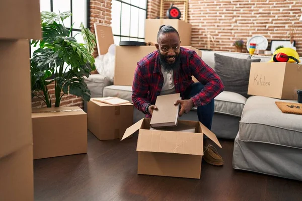 Young African American Man Unpacking Books Cardboard Box New Home — Stok fotoğraf