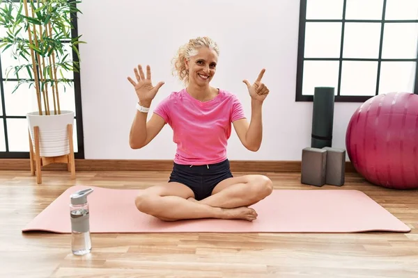 Middle Age Blonde Woman Sitting Yoga Mat Showing Pointing Fingers — Stock Photo, Image