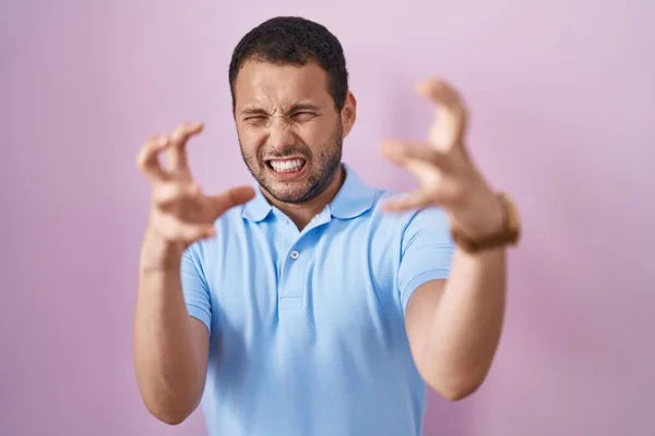 ピンクの背景に立っているヒスパニック系の男は怒りに不満を叫び 手を絞殺しようとすると 怒って叫んで — ストック写真