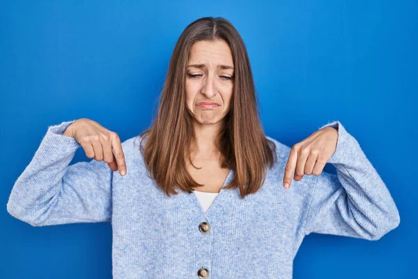 Young Woman Standing Blue Background Pointing Looking Sad Upset Indicating — Stockfoto