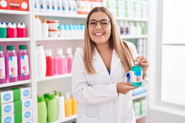 Young Blonde Woman Working Pharmacy Drugstore Holding Syrup Winking Looking — Foto de Stock