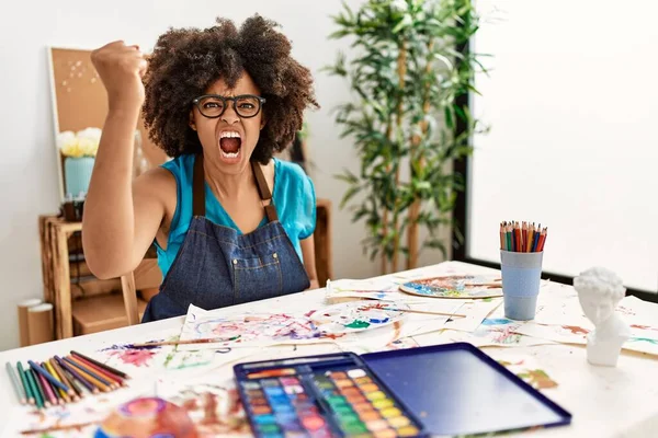 一个美丽的非洲裔美国女人 在艺术工作室里画着非洲裔的头发 她生气地举起拳头 怒气冲冲地大叫着 愤怒和好斗的概念 — 图库照片