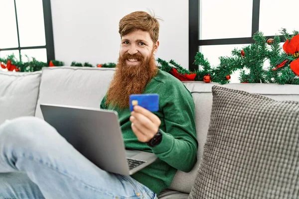 Young Redhead Man Using Laptop Credit Card Sitting Christmas Decor — Stockfoto