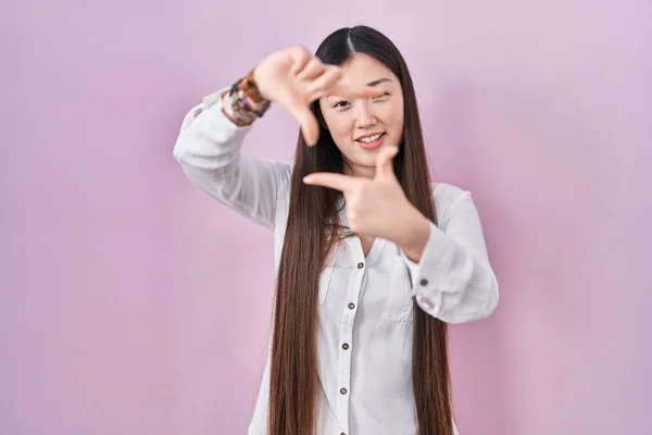 Китайская Молодая Женщина Стоящая Розовом Фоне Улыбаясь Делает Рамку Руками — стоковое фото