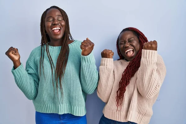 Две Африканки Стоящие Синем Фоне Радовались Удивлялись Успеху Поднятыми Руками — стоковое фото