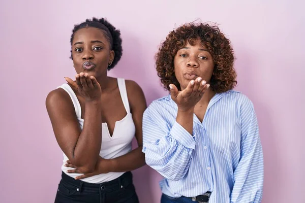 Two African Women Standing Pink Background Looking Camera Blowing Kiss — Stok fotoğraf