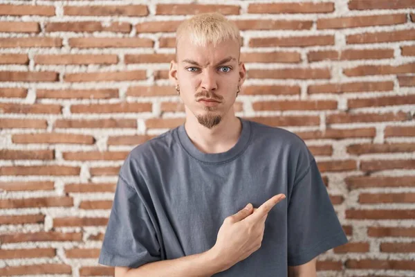 レンガの壁の上に立っている若い白人男性は心配し 額で緊張し 心配し 驚きの表情 — ストック写真